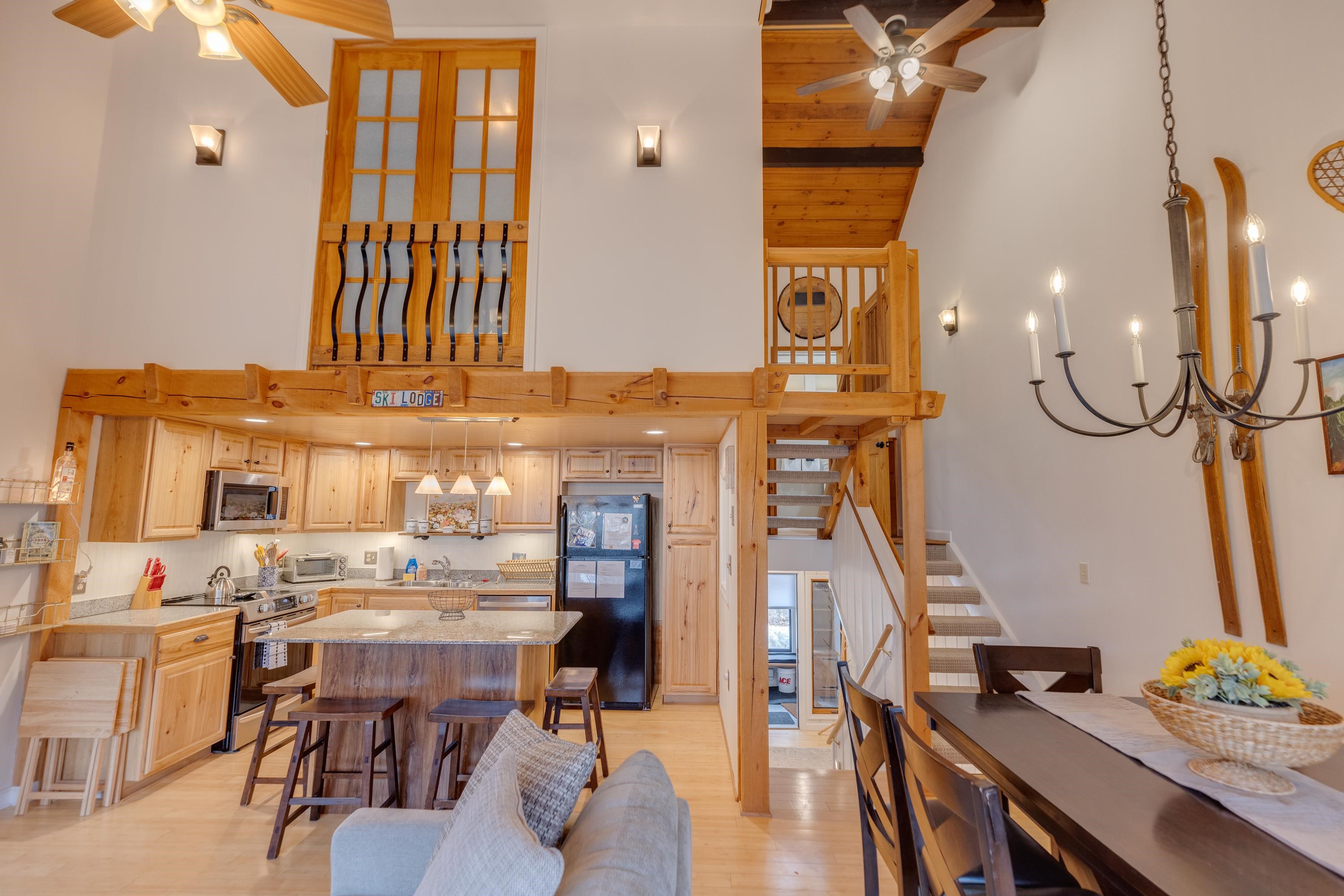 Open-plan kitchen and dining area with a wood island, staircase, and timber-framed loft.