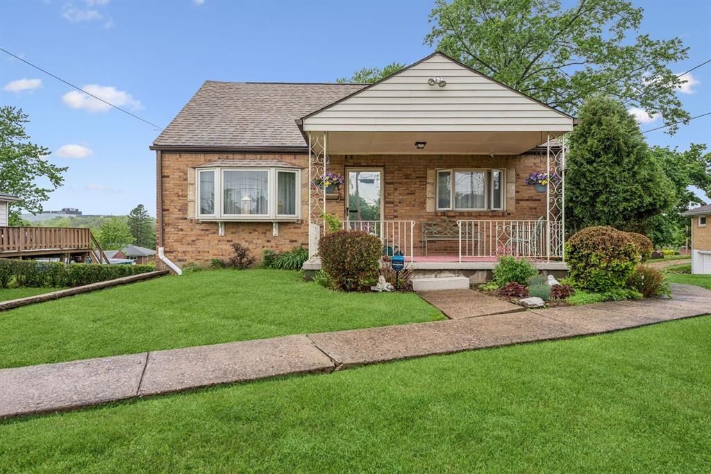 Brick home with a covered porch and bay window, set behind a broad green lawn.