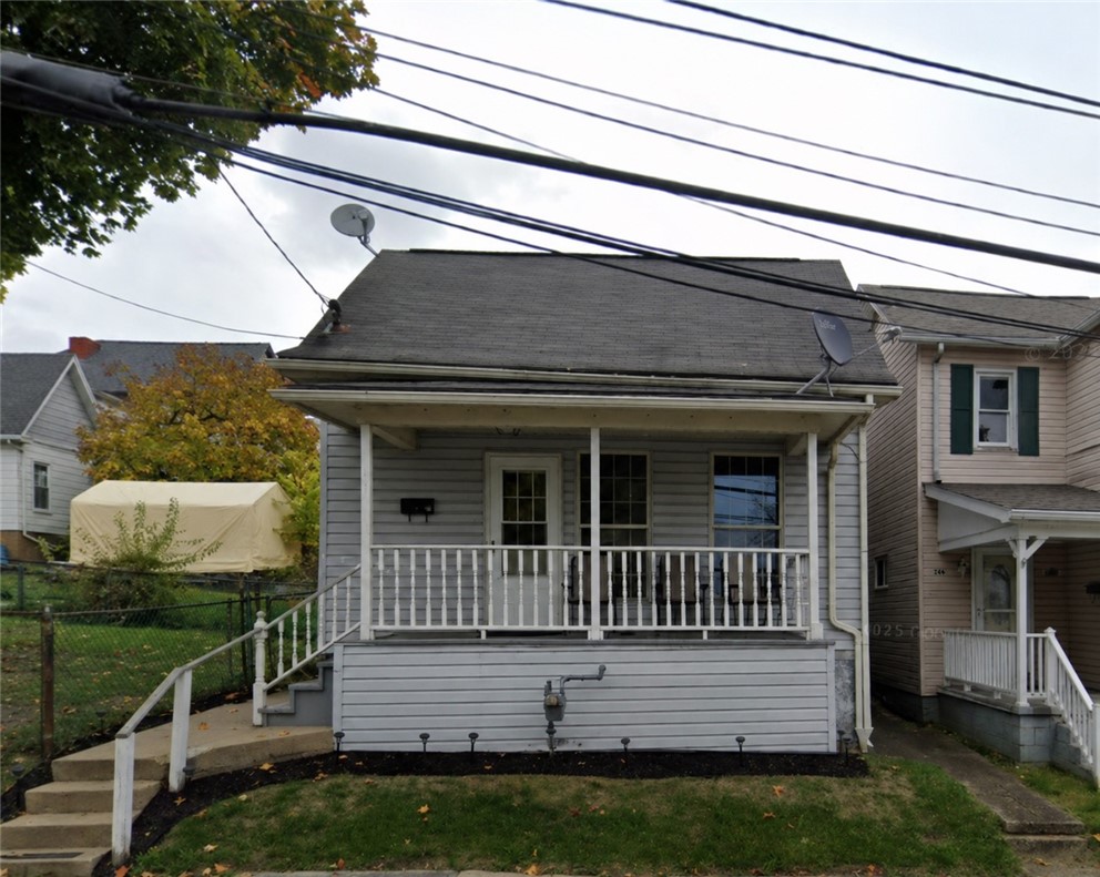 Gray-sided house with a covered porch, white railings, and front steps.