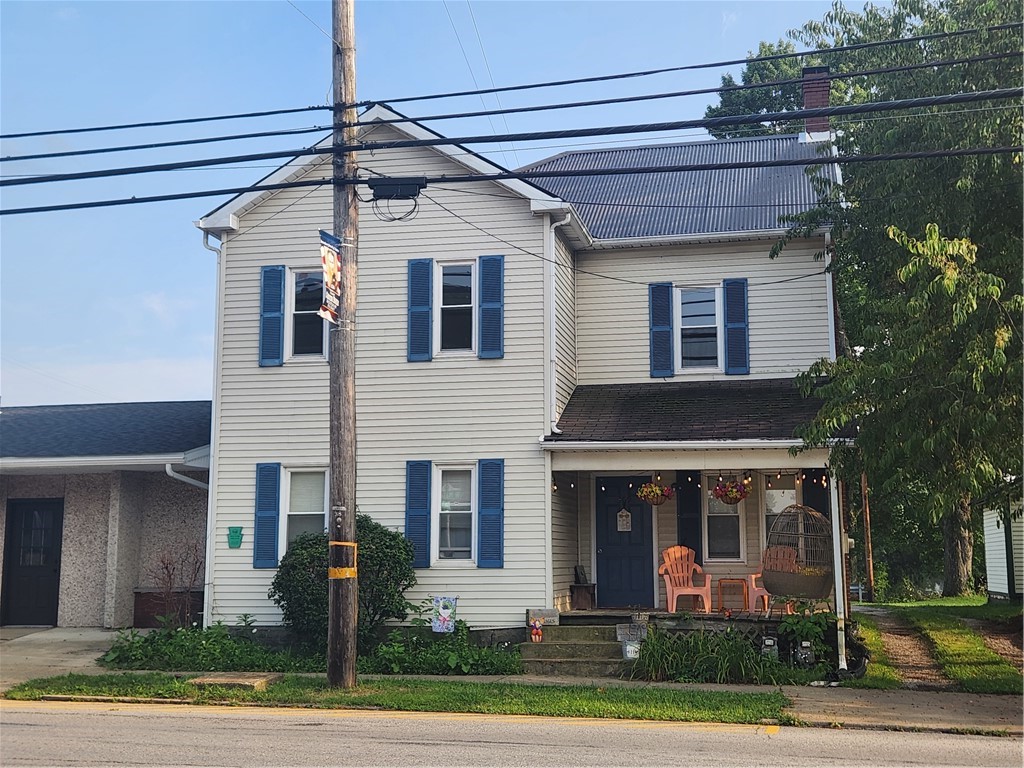 Two-story white house with blue shutters and a furnished covered porch.
