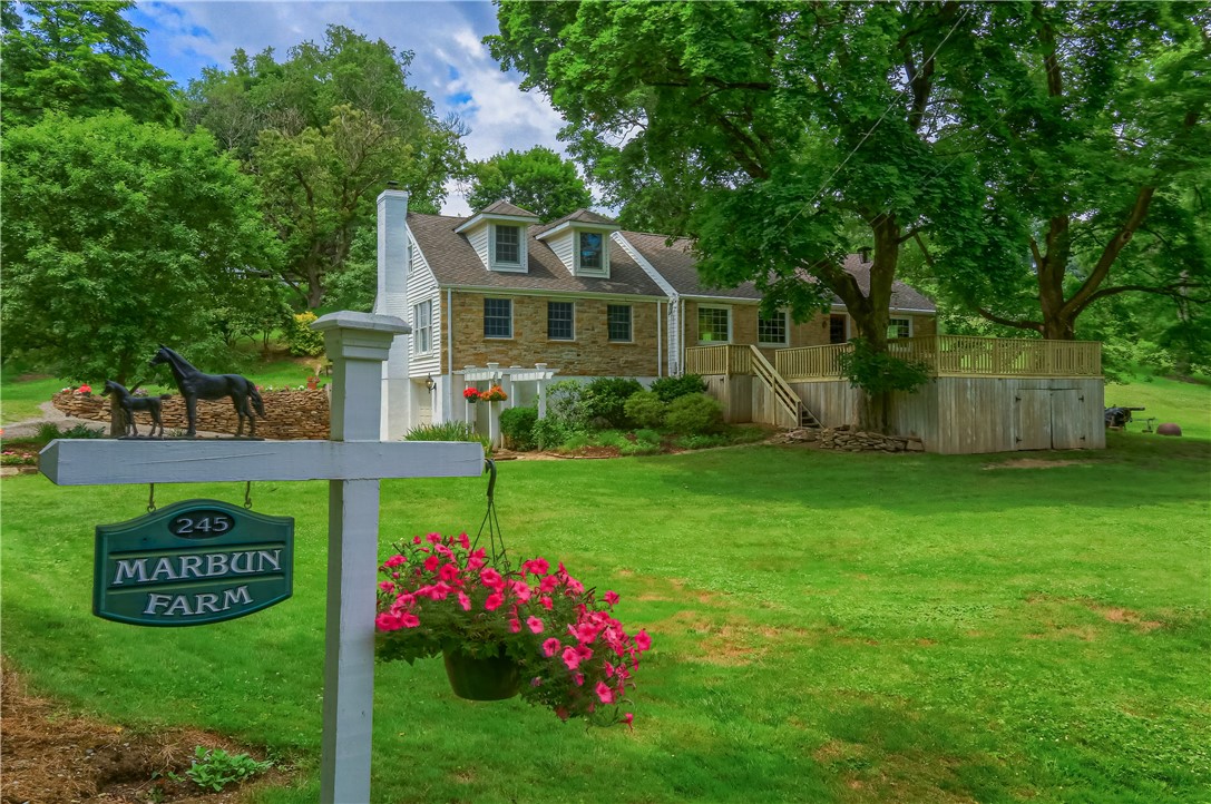 Stone-and-siding home with a raised deck behind a Marbun Farm sign.
