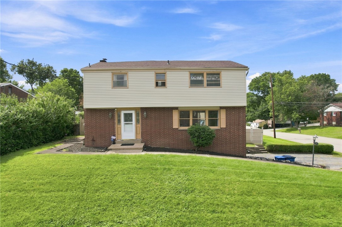 Two-story brick and siding house with a broad green lawn and front entrance.