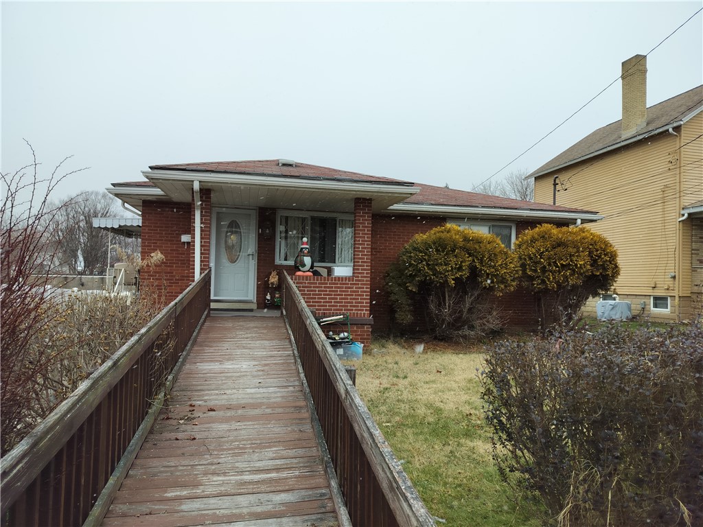 Single-story brick house with a long wooden ramp leading to its front entrance.