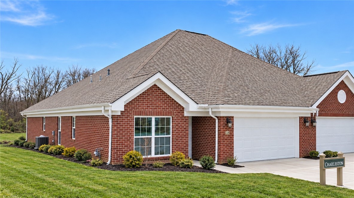 Red-brick home with a large roof, white double garage doors, and landscaped lawn.