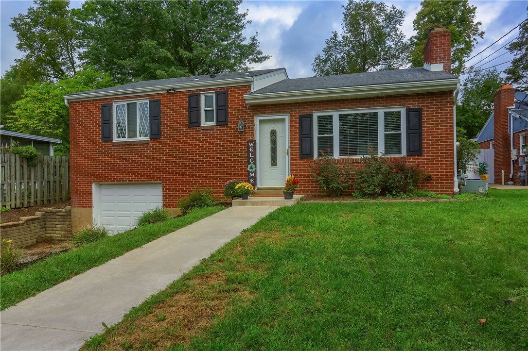 Red brick split-level house with black shutters, a white garage door, and a walkway through the lawn.