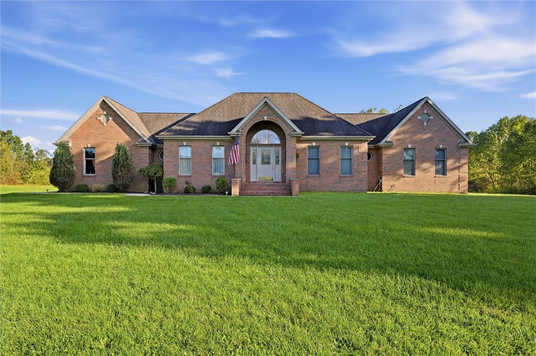 Brick home with a central arched entry, American flag, and broad green lawn.