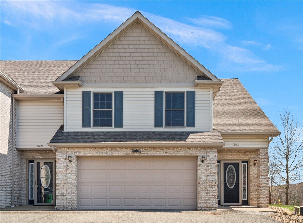 Two-unit home with a brick facade, white siding, blue shutters, and a wide garage door.