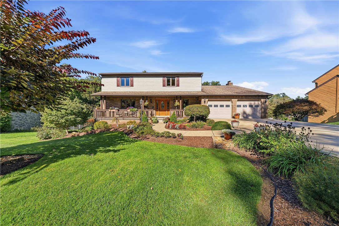 Two-story home with a covered porch, double garage, landscaped gardens, and a broad green lawn.