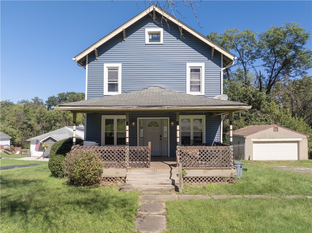 Blue two-story house with a covered porch and detached garage, viewed from the front.