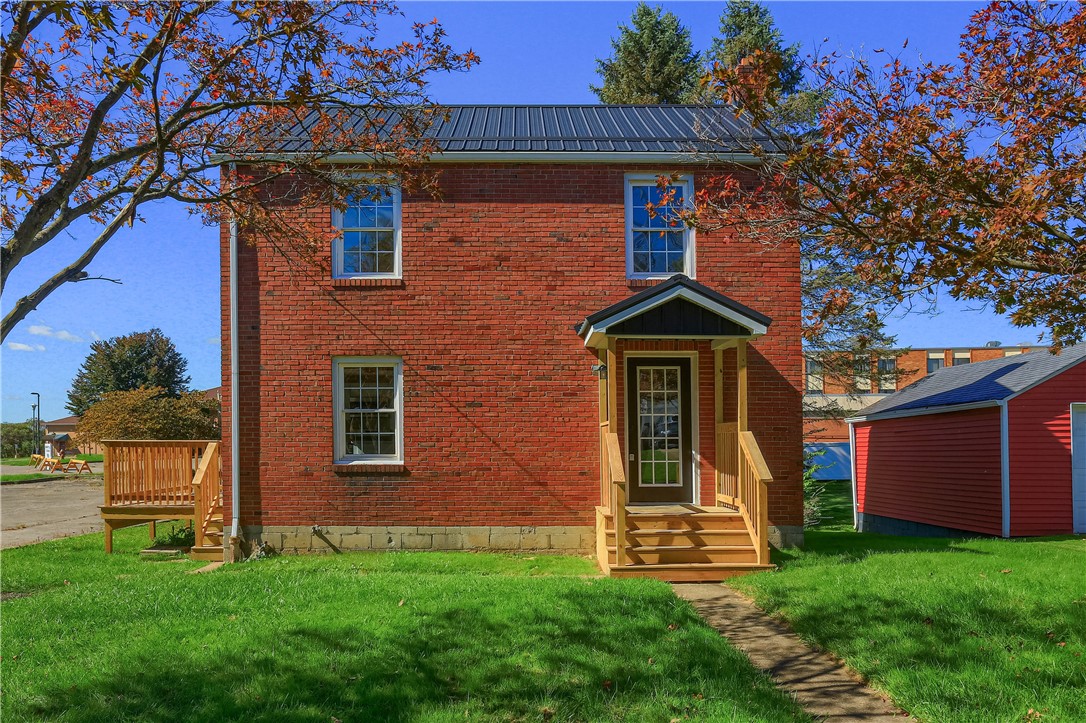 Red brick two-story house with a covered wooden entry porch and metal roof.