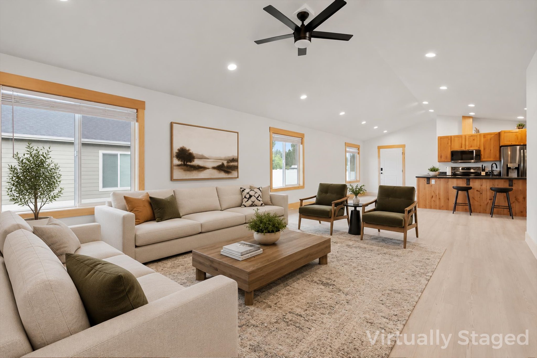 Virtually staged living room with cream sofas, olive chairs, and an open kitchen with wood cabinetry.
