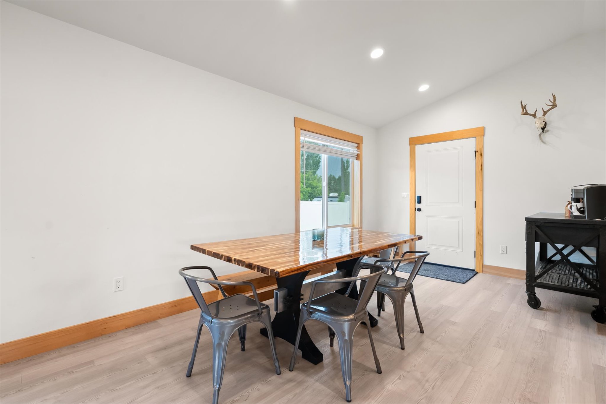 Dining area with a live-edge wood table, metal chairs, and a mounted deer skull.