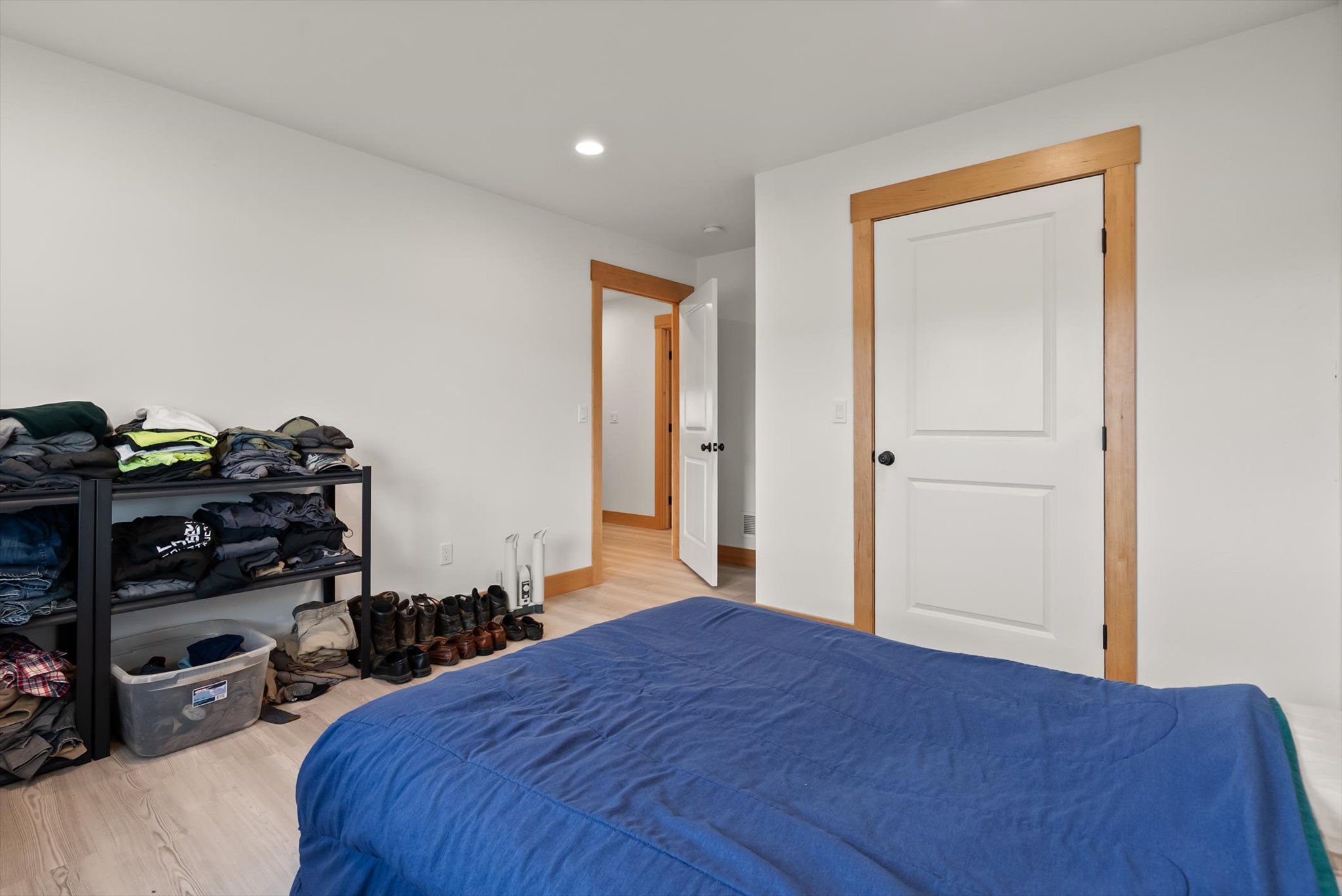 Bedroom with a blue-covered bed, clothing shelves, and light wood trim.