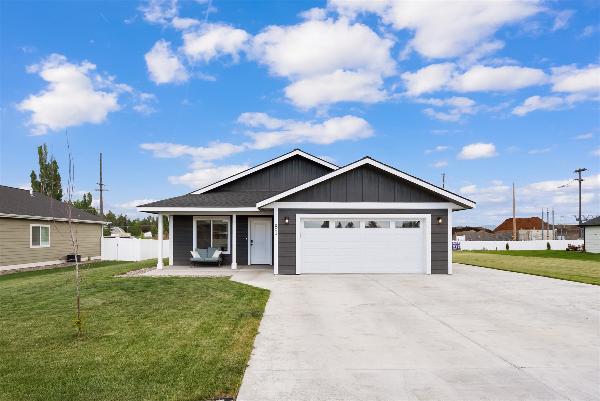 Gray single-story home with a two-car garage, covered porch, and wide concrete driveway.