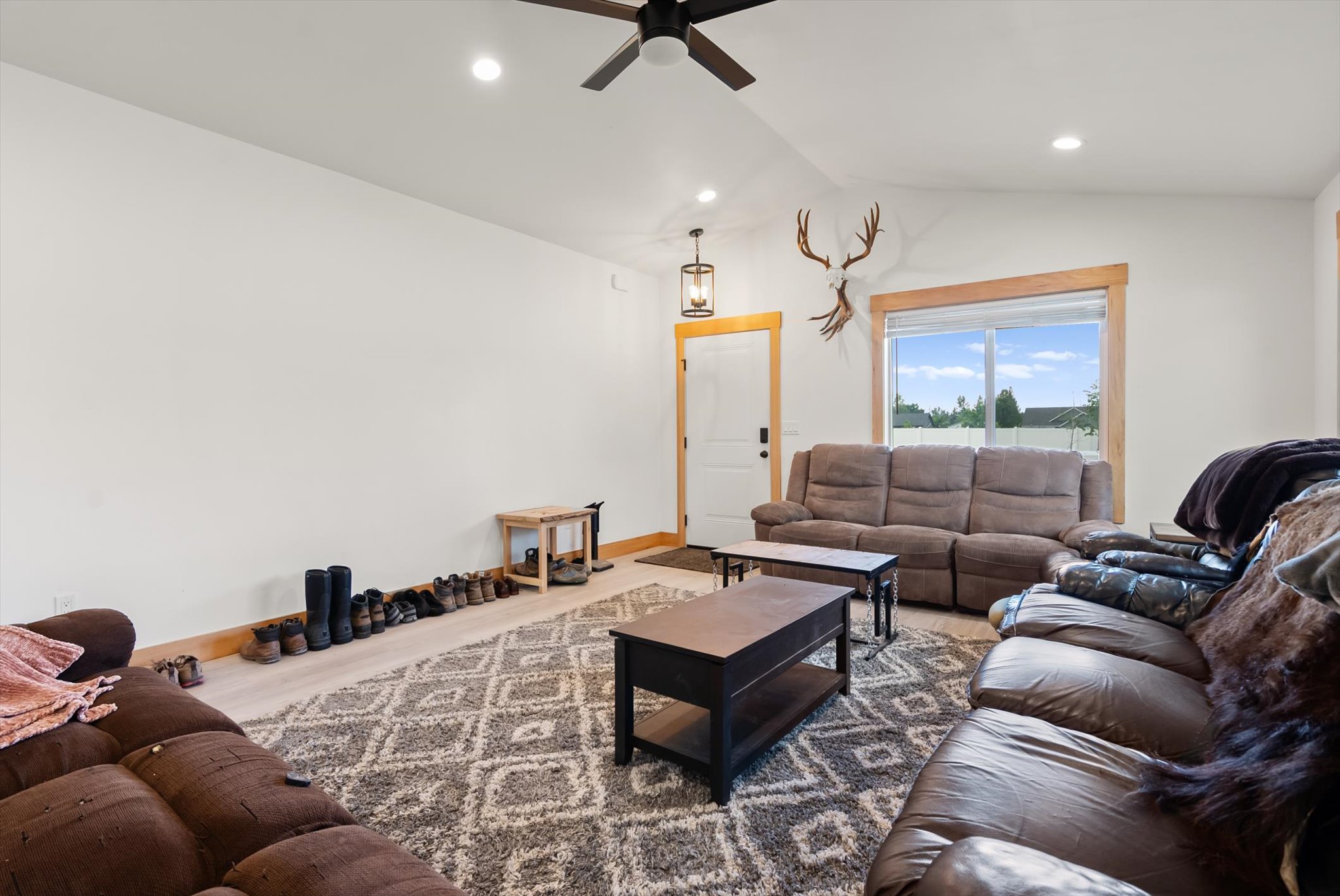 Living room with brown sofas, two coffee tables, a patterned rug, and a large wood-trimmed window.