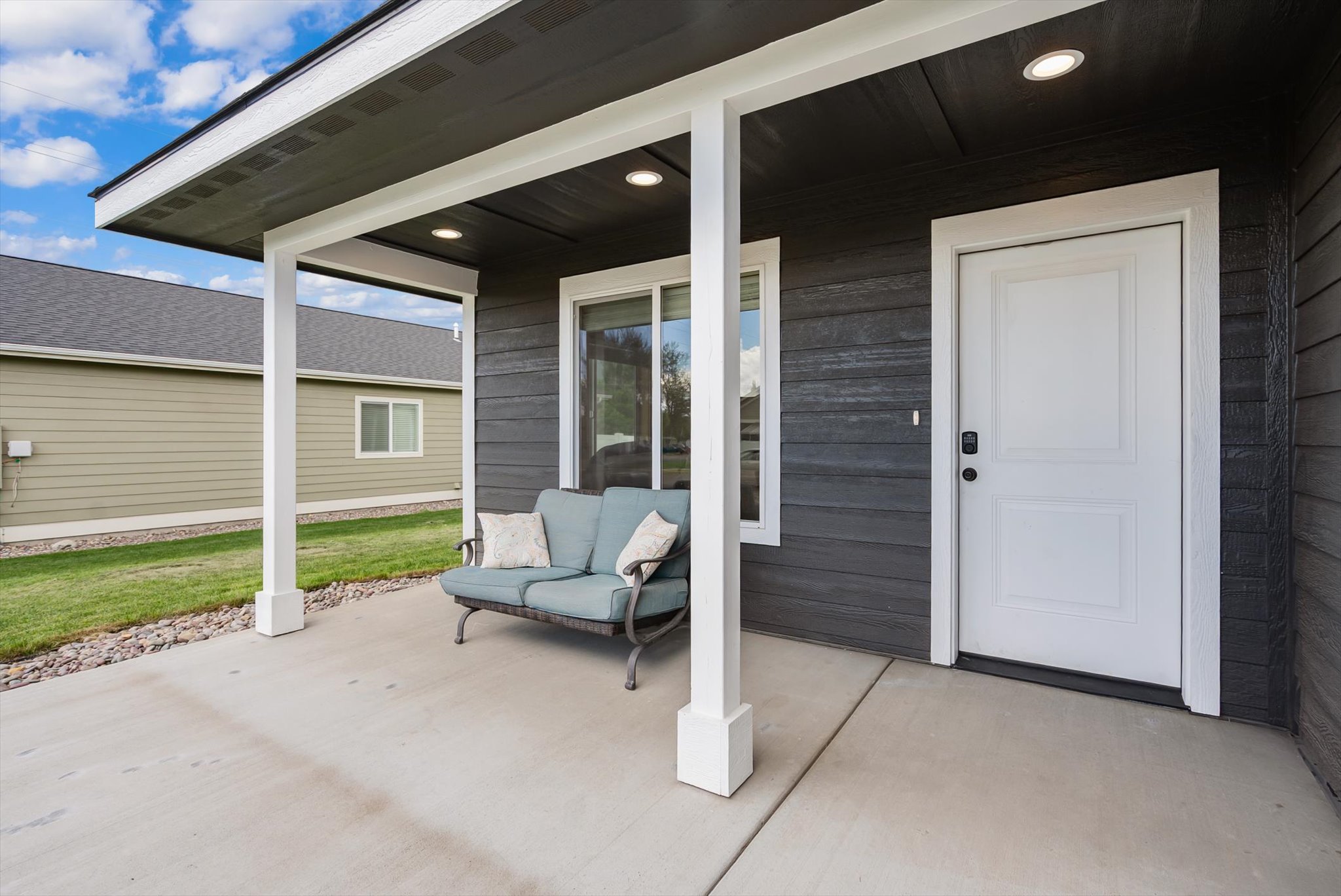 Covered front porch with a cushioned loveseat beside the white entry door.