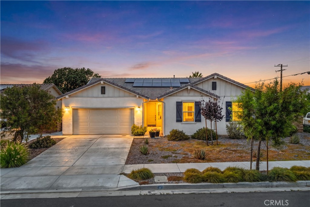Single-story home with a yellow front door, attached garage, and rooftop solar panels at dusk.