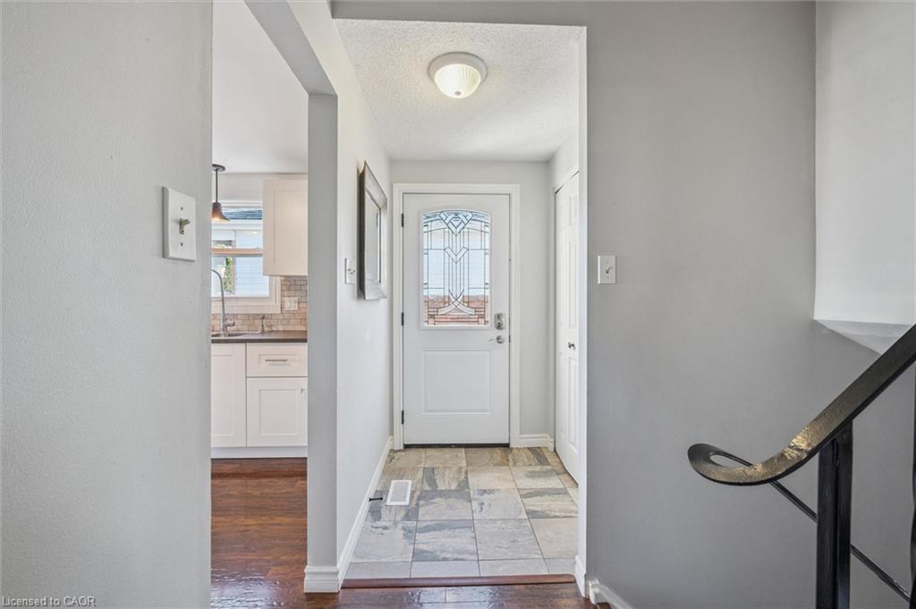 Entry hall with multicolored tile flooring, decorative-glass front door, and staircase railing.