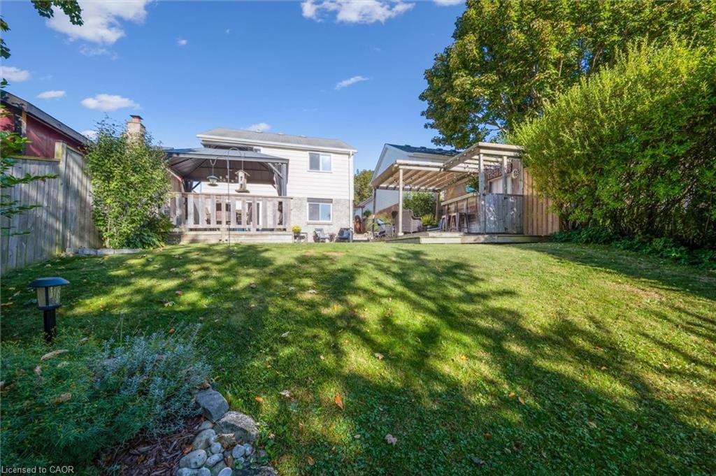 House viewed from a grassy backyard with a raised deck and covered patio.