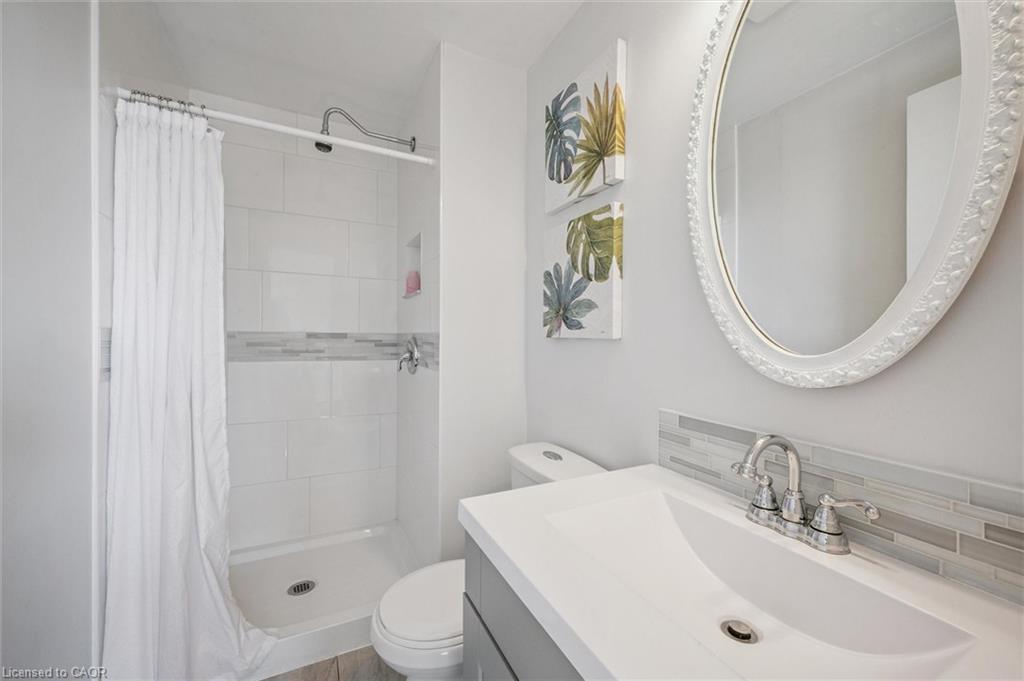 Bathroom with a white vanity, ornate oval mirror, and tiled shower with a white curtain.