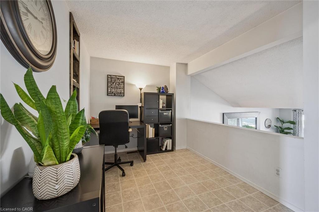 Upper-level home office with a desk, black shelving, sloped ceiling and large potted snake plant.