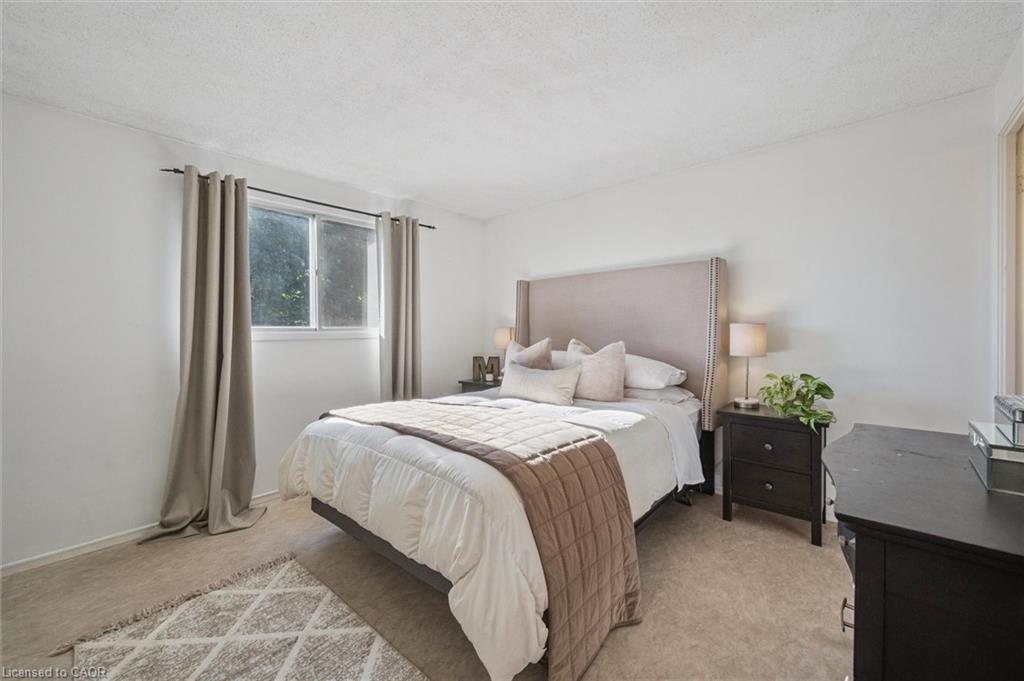 Staged bedroom with a white bed, taupe throw, upholstered headboard, and curtained window.