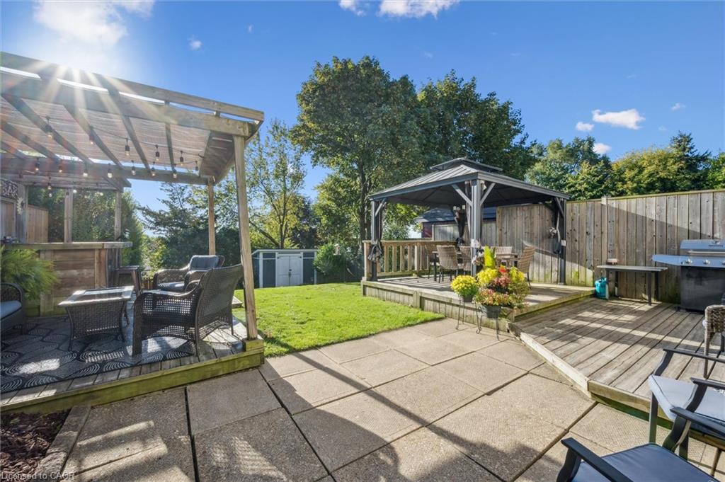 Backyard with a lawn, paved patio, pergola seating area, gazebo, and wooden deck.