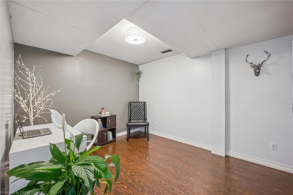 Small office with a white desk, black chair, wood flooring, and deer-head wall decoration.
