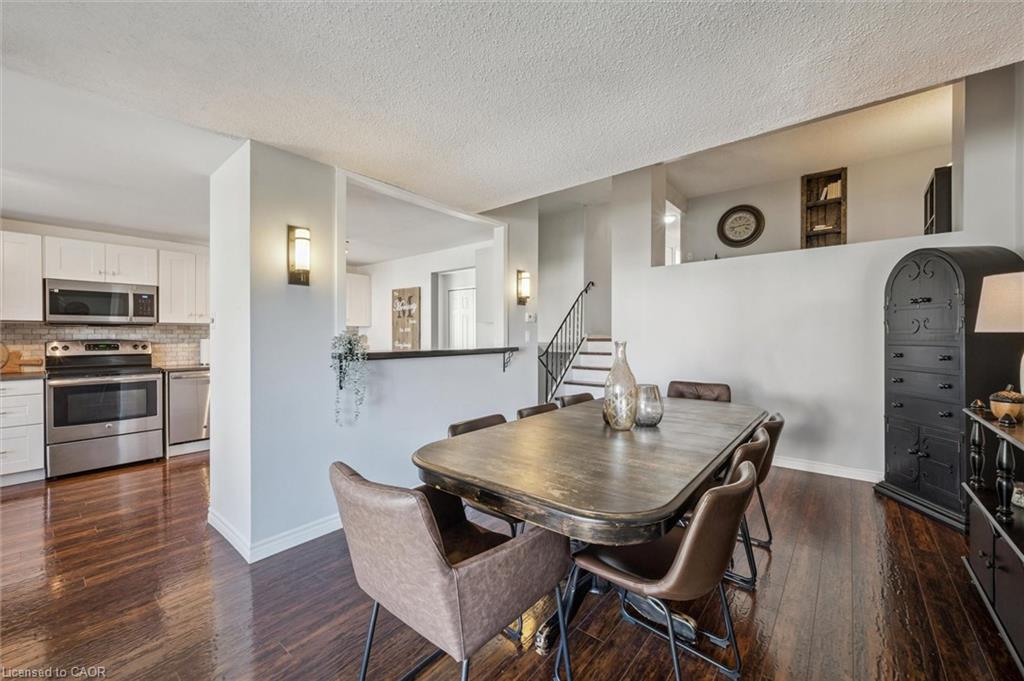 Dining room with a dark wood table, hardwood floors, and an adjoining white kitchen.