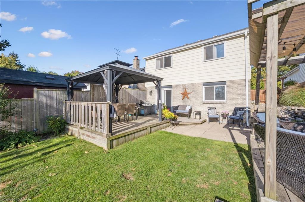 Backyard with a covered pergola, outdoor seating, lawn, and paved patio beside the house.