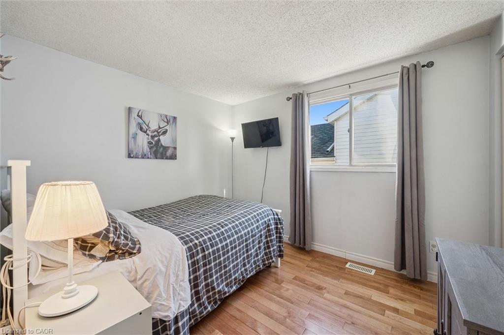 Bedroom with two beds, hardwood floors, deer artwork, and a wall-mounted television.