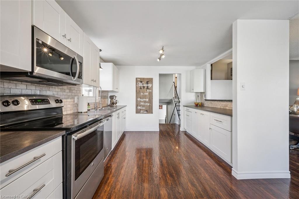 Renovated kitchen with white cabinetry, stainless steel appliances, and warm wood-look flooring.