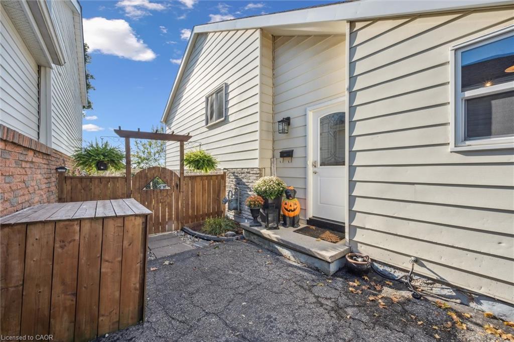 Side entrance of a light-sided house beside a fenced paved courtyard with Halloween decorations.
