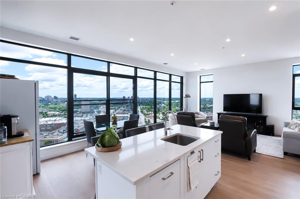 Open-plan condo kitchen and living room with a white island and floor-to-ceiling windows overlooking the city.