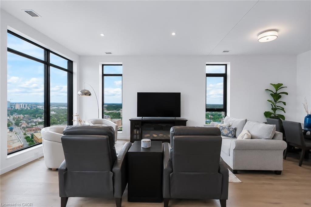 High-rise condo living room with broad city views, a white sofa and two dark armchairs.
