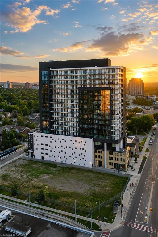 Modern high-rise condominium with white balconies and dark glass, viewed from above at sunset.