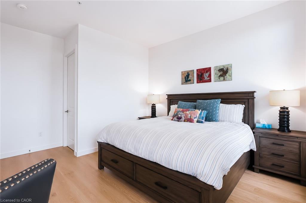 Furnished bedroom with a dark wood bed, striped white bedding, and colorful pillows.