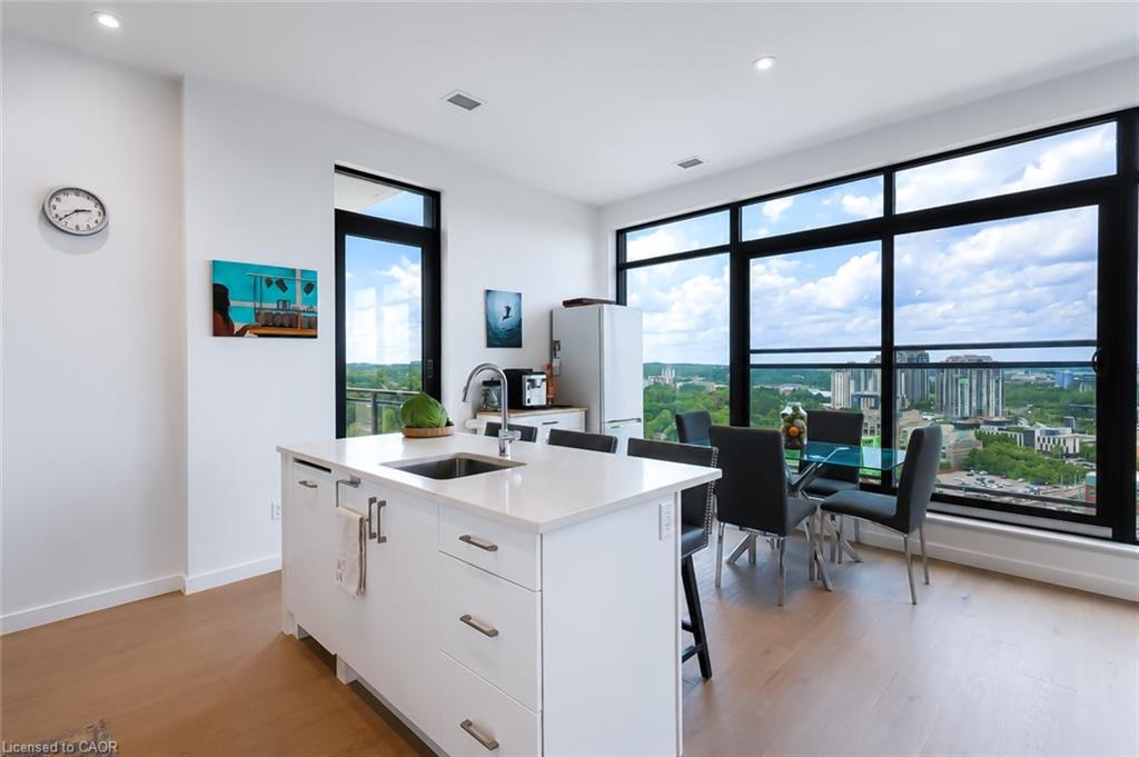 Modern condo kitchen with a white island and floor-to-ceiling windows overlooking the city.