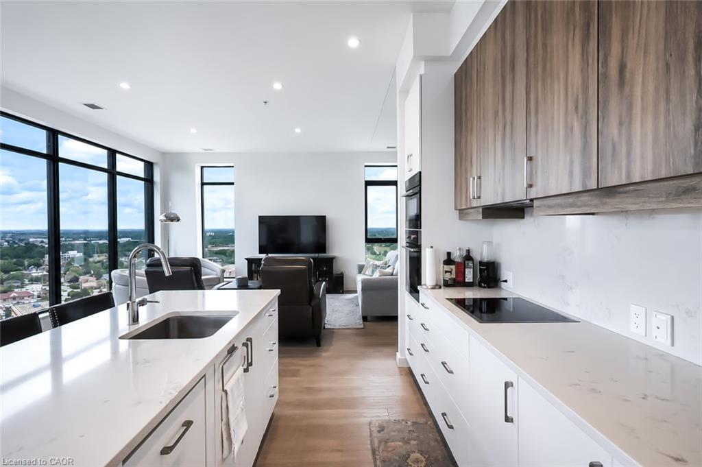 Modern condo kitchen with a white island, wood cabinetry and floor-to-ceiling windows overlooking Waterloo.