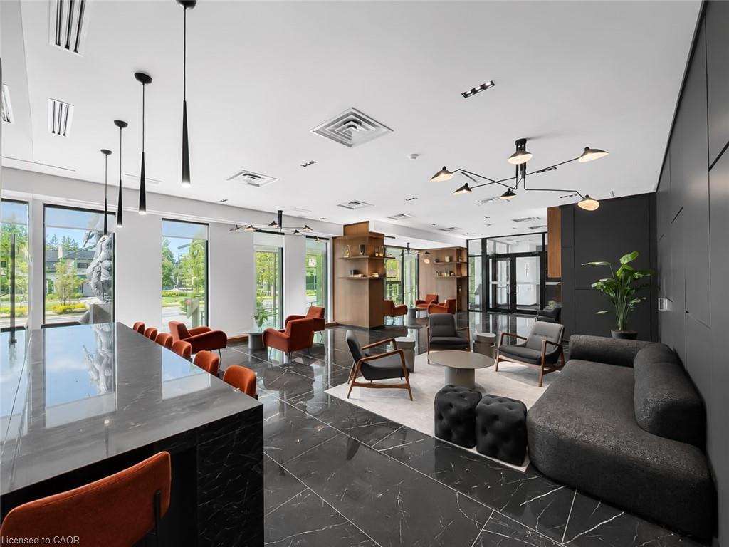 Condominium lobby lounge with floor-to-ceiling windows, orange chairs, and a dark sectional sofa.