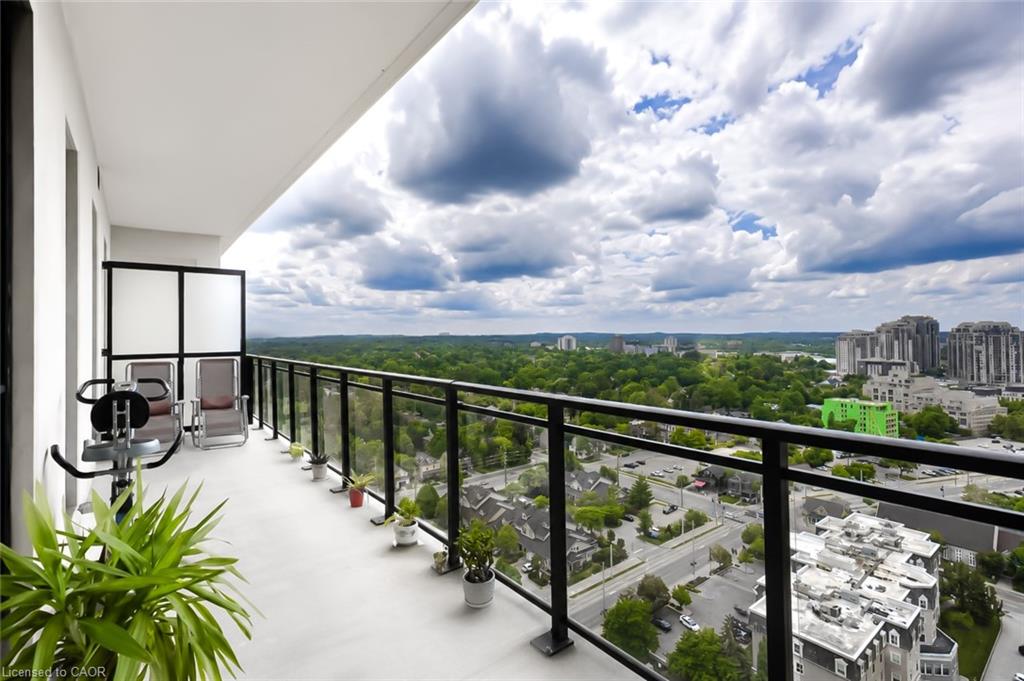 Condo balcony with chairs and potted plants overlooking Waterloo’s tree canopy and city buildings.