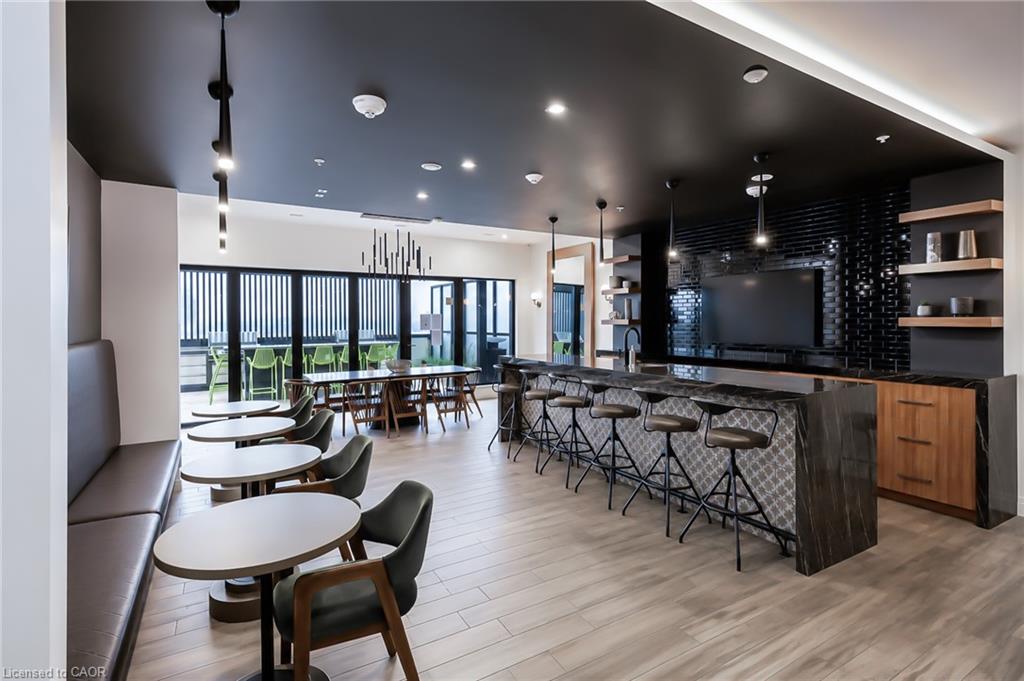Condominium lounge with a long bar, dining tables, and banquette seating.