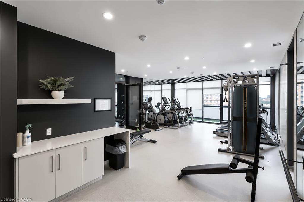 Condominium fitness room with cardio machines and strength equipment beside large windows.
