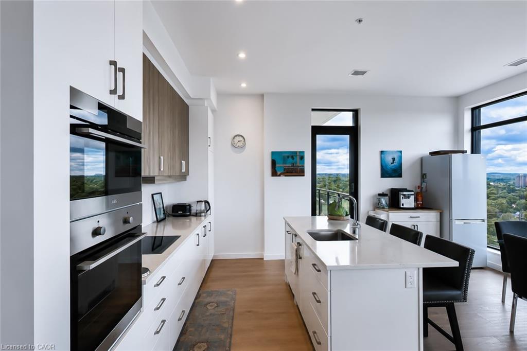 Modern condo kitchen with a large white island and expansive windows overlooking greenery.