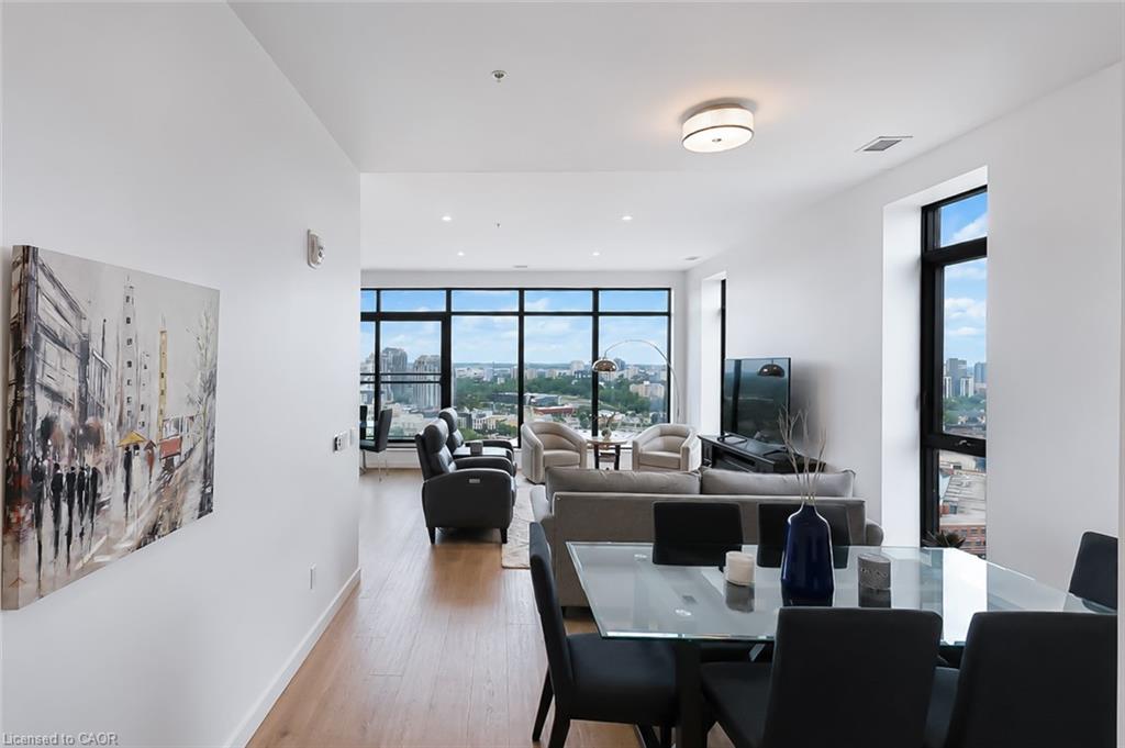 Open-plan condo living and dining room with floor-to-ceiling windows overlooking the city.