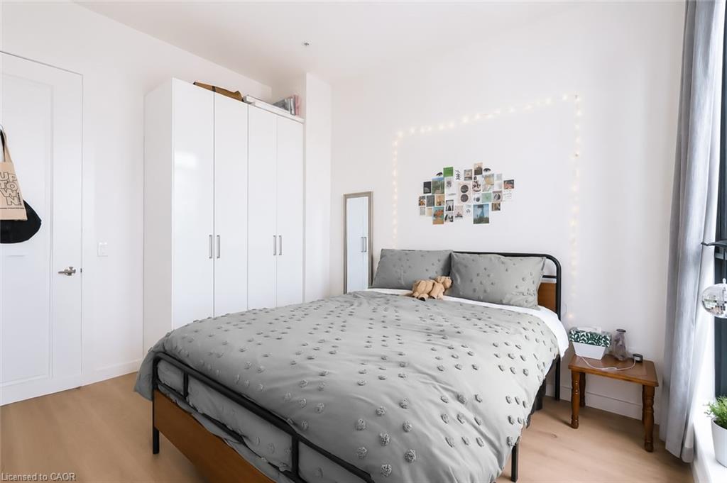 Bedroom with a gray patterned bed, white wardrobes, and photos framed by string lights.