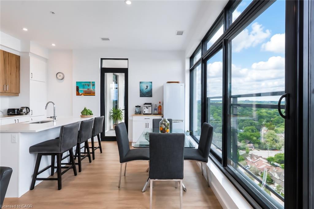 Condo dining area beside floor-to-ceiling windows overlooking treetops and rooftops.