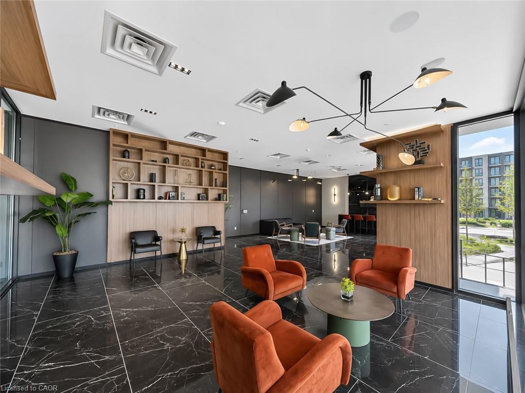 Condominium lounge with orange armchairs, built-in wood shelving, and large windows.