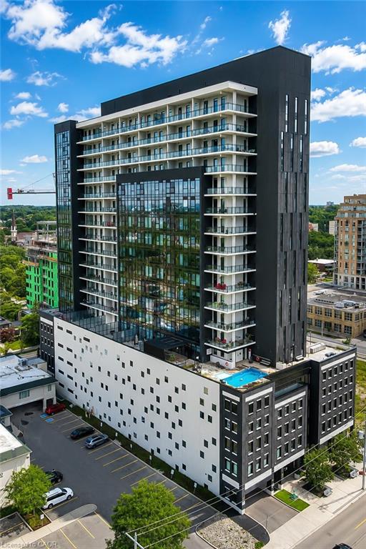 Modern condominium tower with glass balconies, dark cladding, and a rooftop swimming pool.