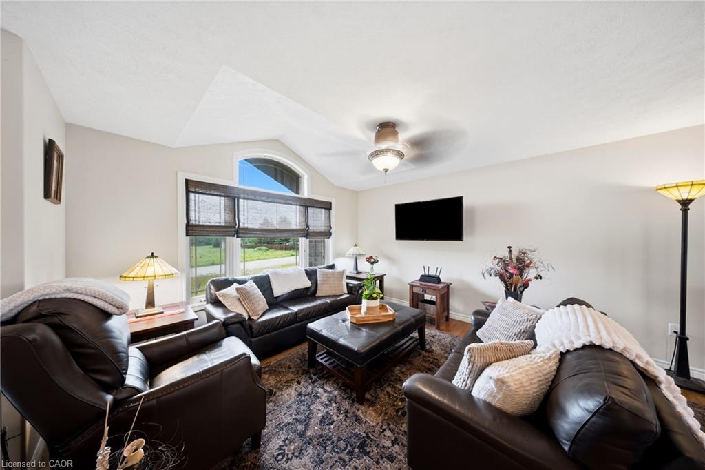 Living room with dark leather seating, a patterned rug, and a large window with blinds.